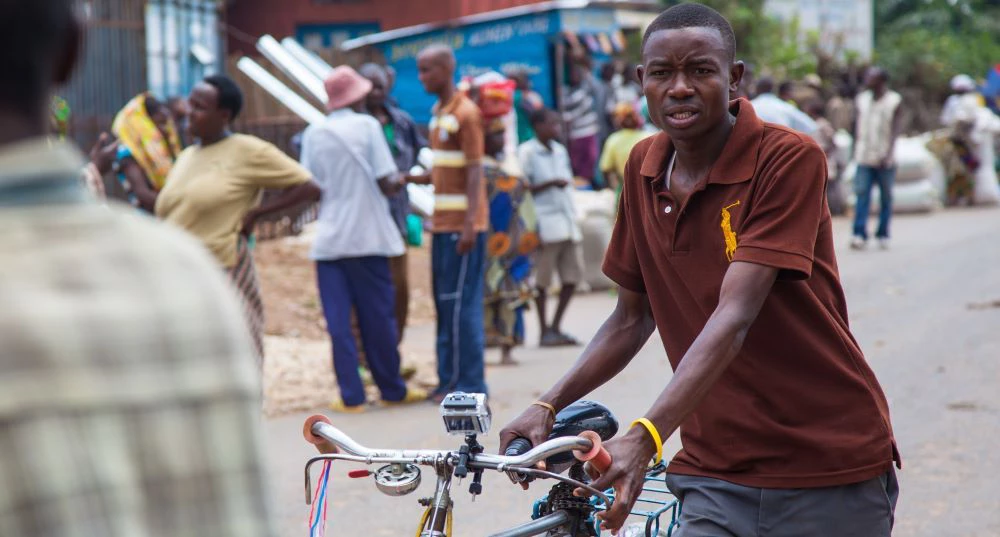 An image of a Burundi high school student with his bicycle.