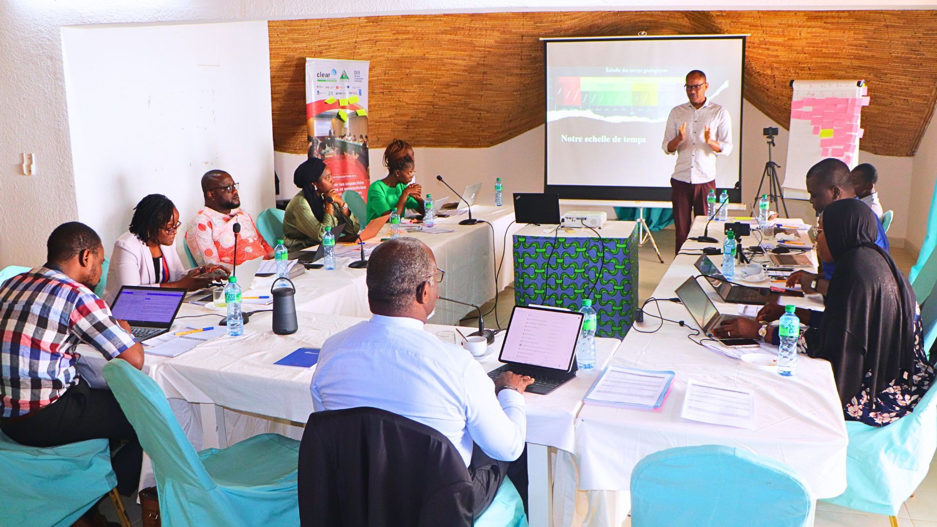 People seated around a conference table watching speaker delivering a presentation