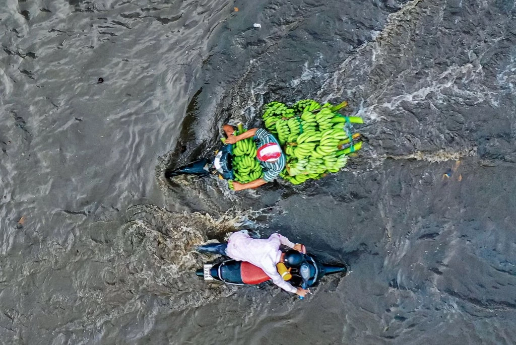 Residents in Ho Chi Minh City try to cross a flooded road. Photo: Quynh Danh/Zing News