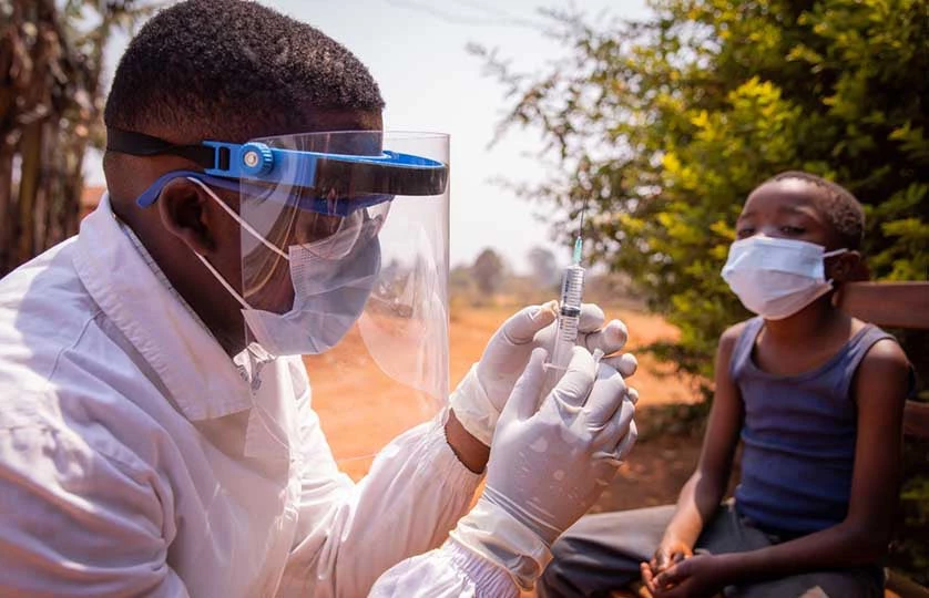 Doctor prepares to administer a vaccine on an African child