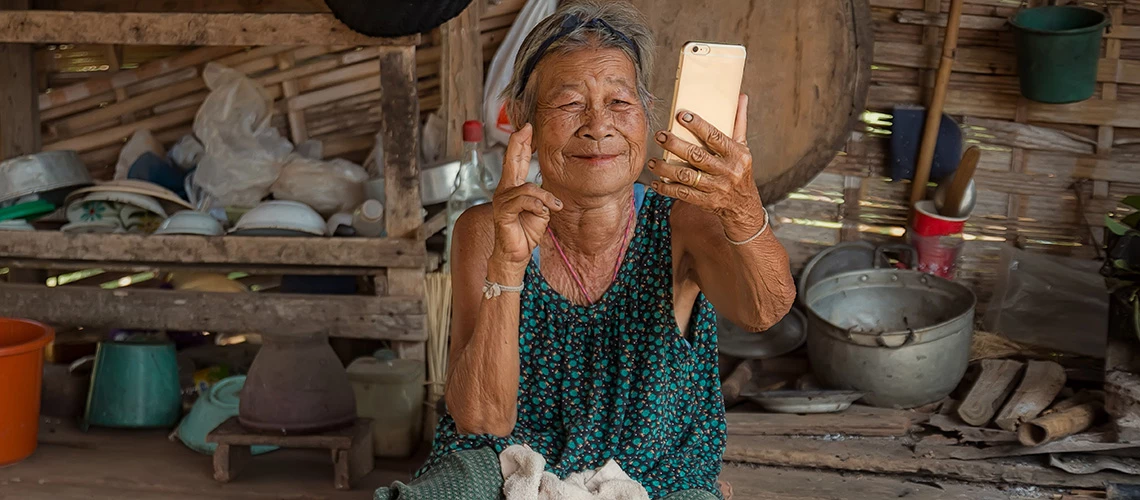 An elderly Asian woman holding a mobile phone. | © shutterstock.com