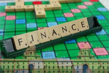 Finance on scrabble board with buildings superimposed on it.