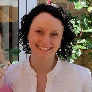 Woman with short dark hair and fair skin, smiling and wearing white blouse