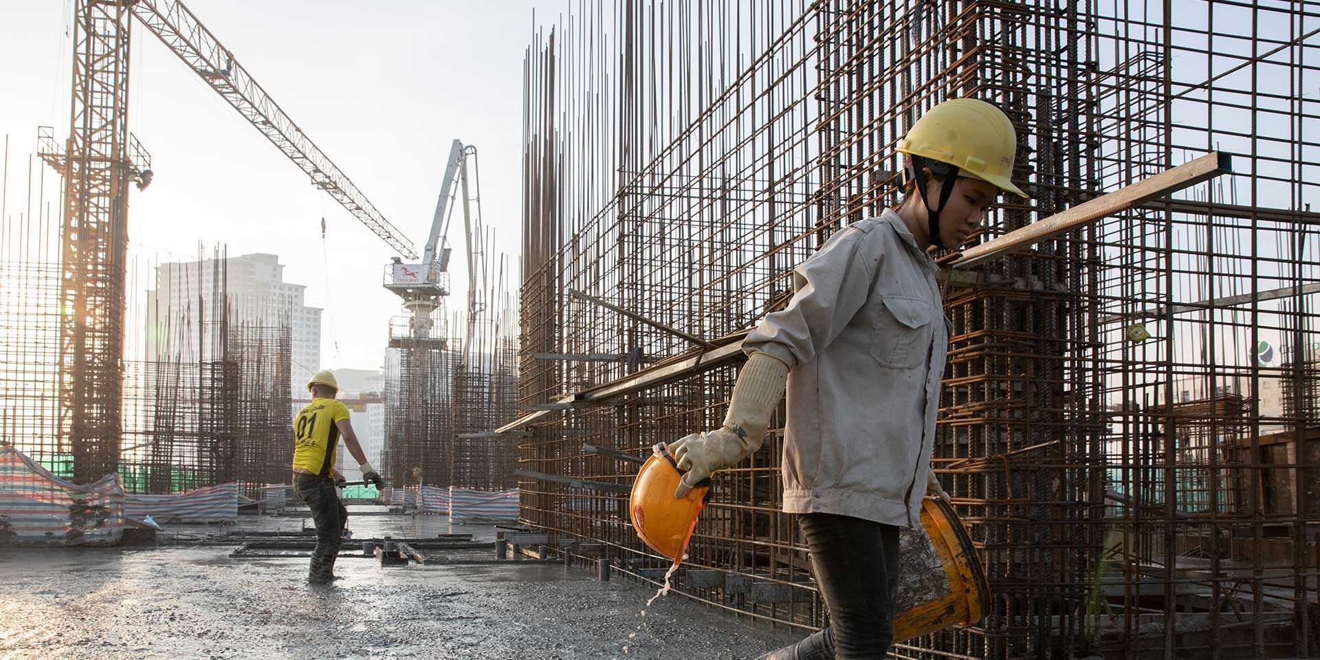 Construction workers carefully lay rebar in preparation to pour concrete on the upper floors of an apartment building Ð the Capital House GroupÕs EcoHome 3 projectÐ in Hanoi, Vietnam on July 28, 2019. This construction project will become an EDGE certified building, an affordable and sustainable housing development in Hanoi. IFC created EDGE (Excellence in Design for Greater Efficiencies)-- a building resource efficiency certification program--especially for emerging markets like Vietnam. Photo © Dominic Chavez/International Finance Corporation