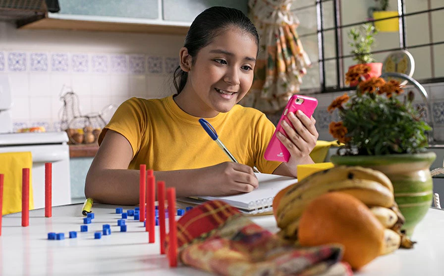 Girl doing her lesson on a phone at home.