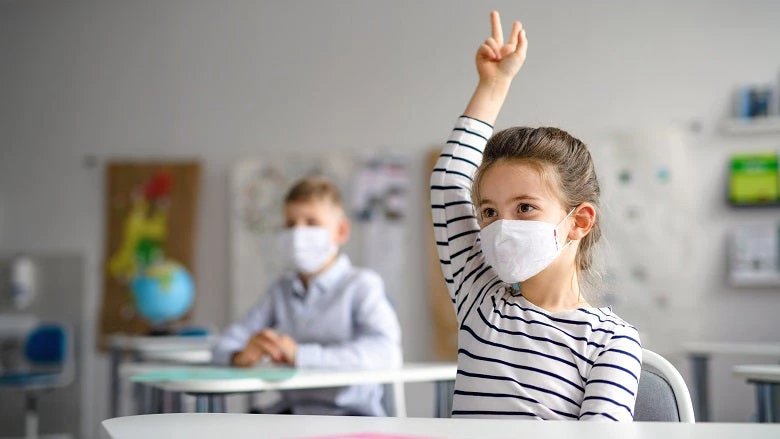 Child with face mask at school. Photo credit: Halfpoint/ Shutterstock