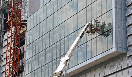 Un ouvrir du bâtiment termine l'installation de vitres sur un immeuble. Trinn Suwannapha / Banque mondiale