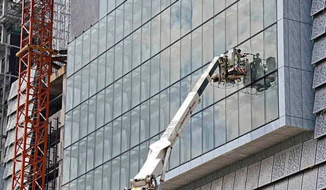 A construction worker finishes sealing glass at a building construction site. Trinn Suwannapha / World Bank