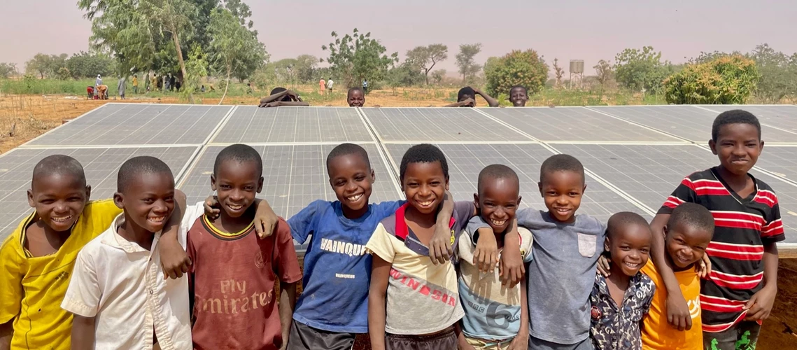 Group of smiley children in front of solar panels in Niger.