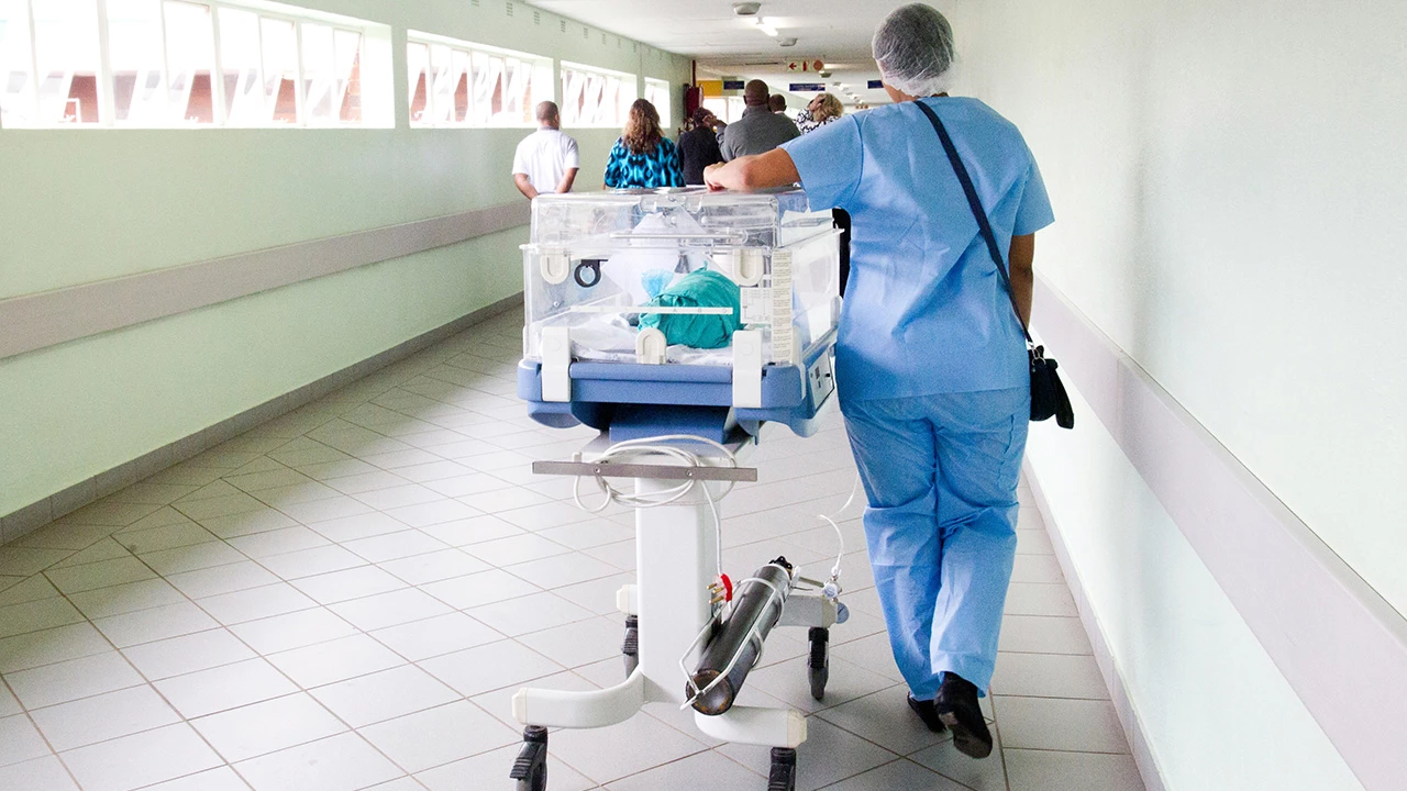 A nurse walking in the hallway of a hospital with incubator