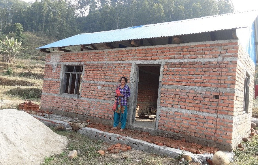 A woman mason in front of her house on progress