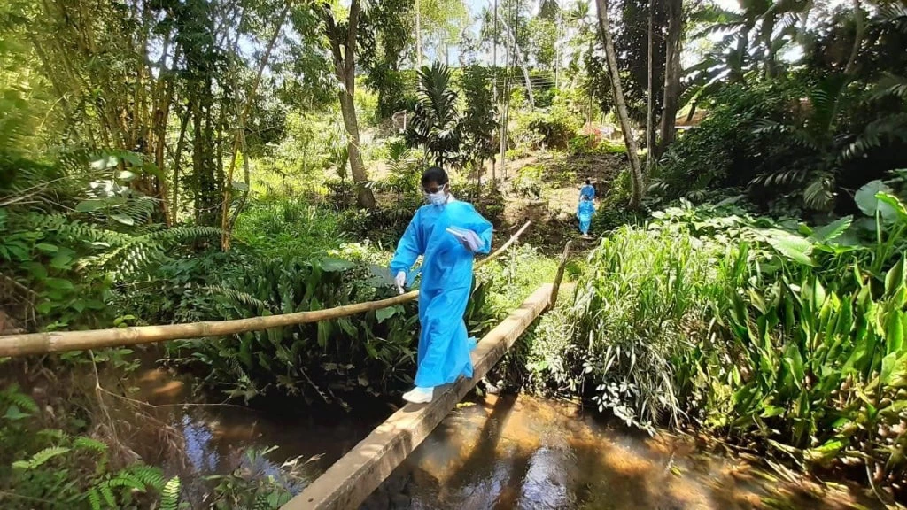 Sri Lankan public health workers trekking through forests to vaccinate people in hard-to-reach areas.