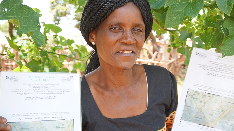 A woman in Zambia holding her new land documents. Photo credit: Rena Singer.