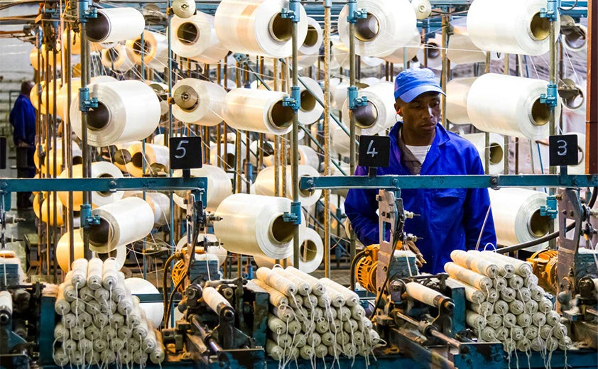 African factory worker on a copwinder weft assembly line loom