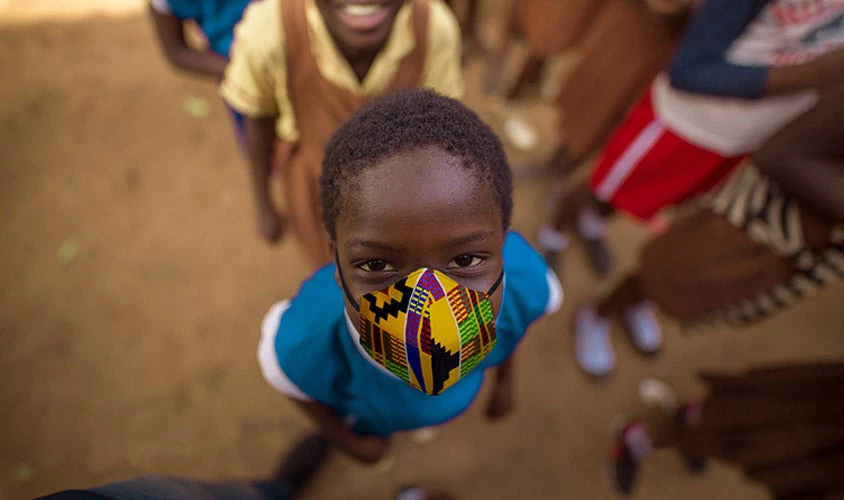 An African school child with colorful pattern print facemask.