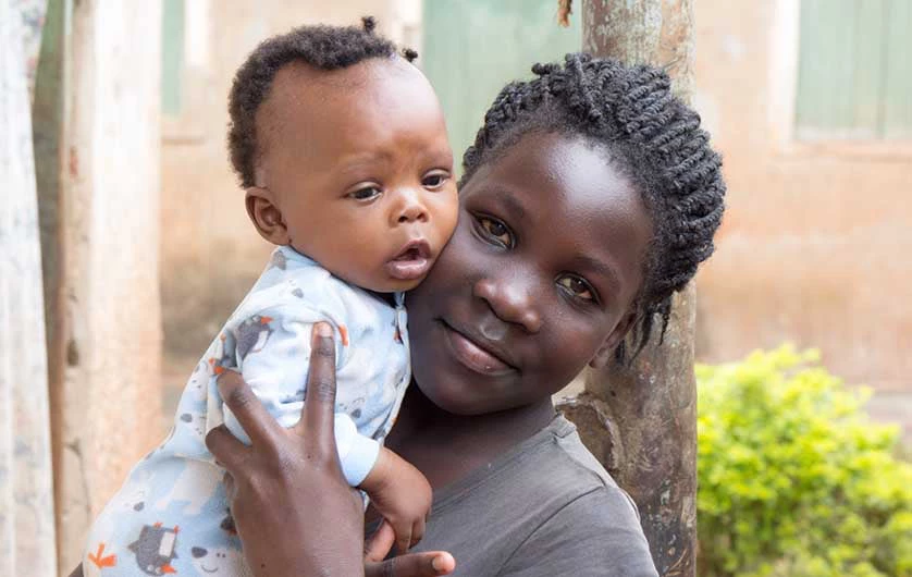 A young African girl holding a baby in her arms.