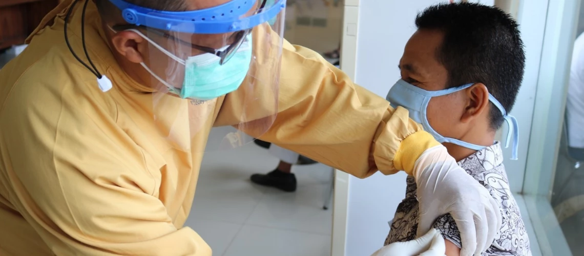 Man receives vaccination shot from a masked health worker