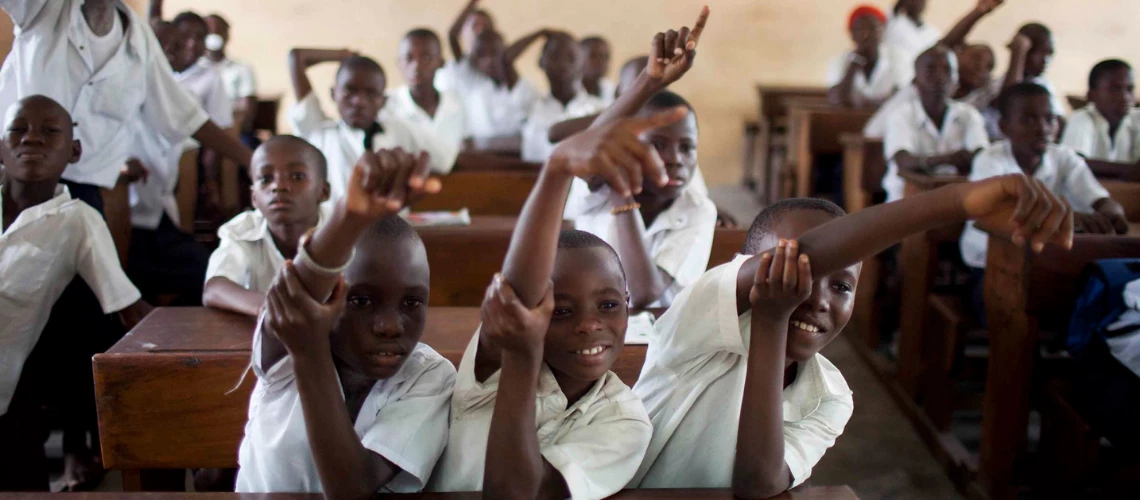 Children in a classroom raising their hands to answer a question