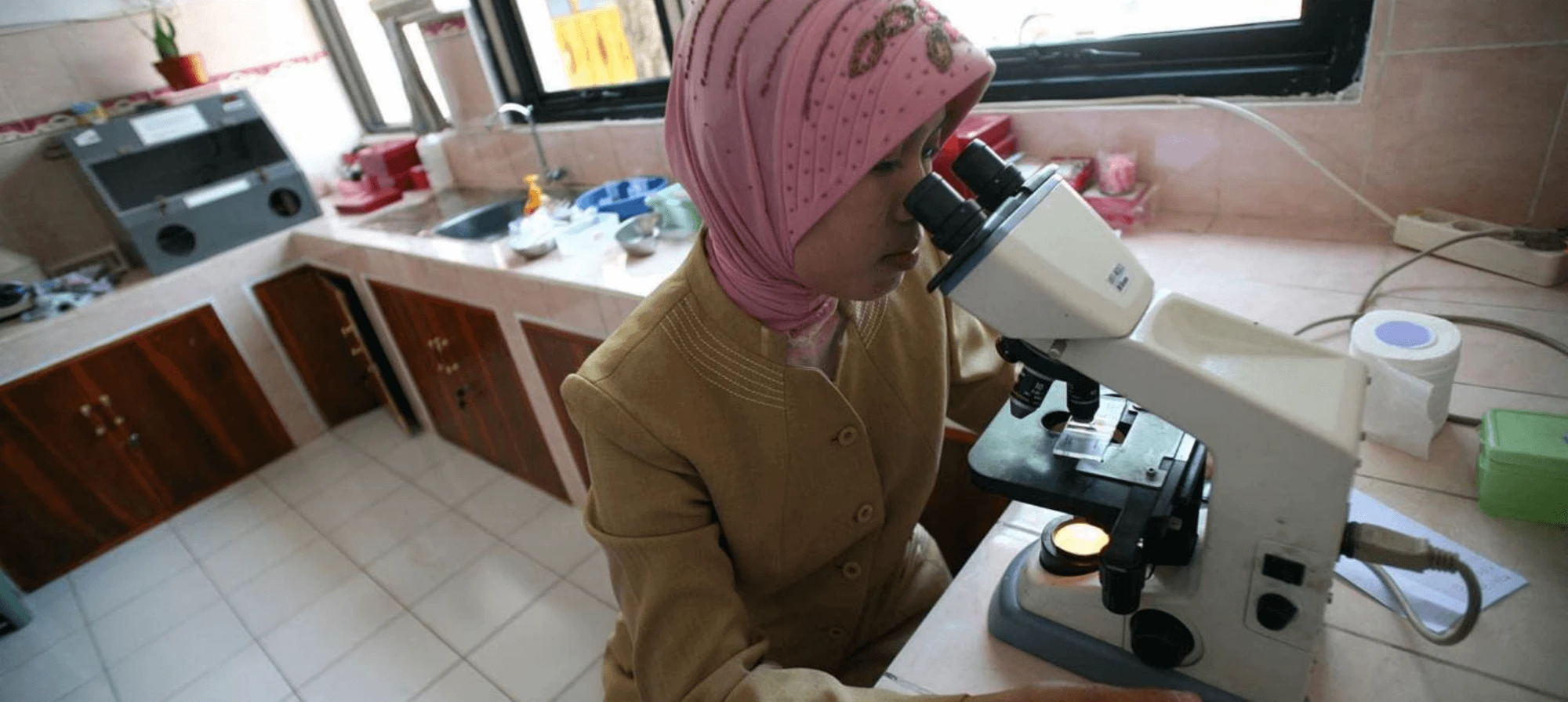 woman looks through a microscope