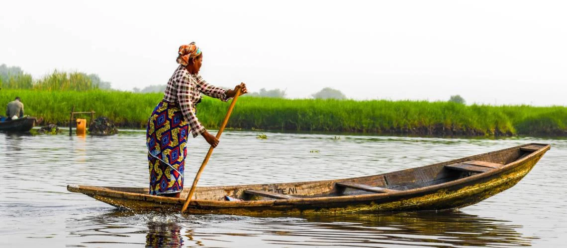 A woman stands on a pirogue on Lake Nokoue, Benin.
