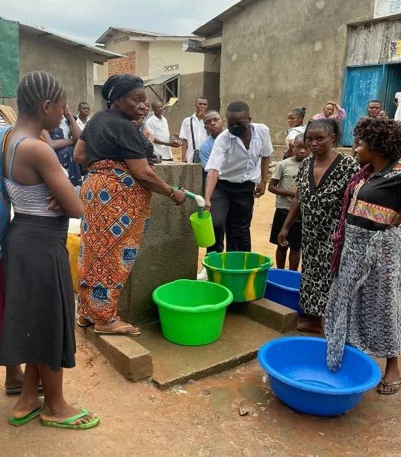 People collecting water from a public spout.