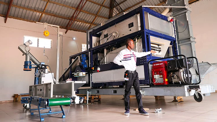 Amos Rutherford Azinu stands in front of his new seed processor