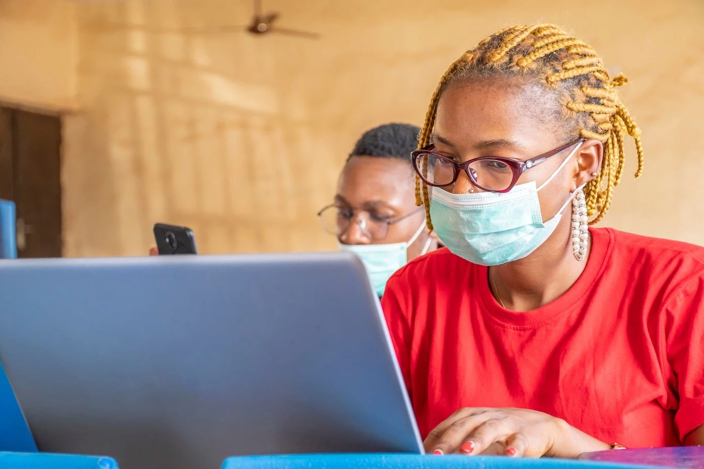 Deux étudiants africains utilisent leur ordinateur portable et leur téléphone au sein d'une classe | Photo : Shutterstock