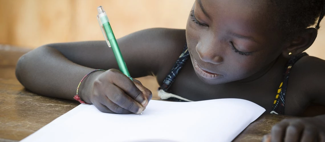 a young girl does homework at a school in Africa