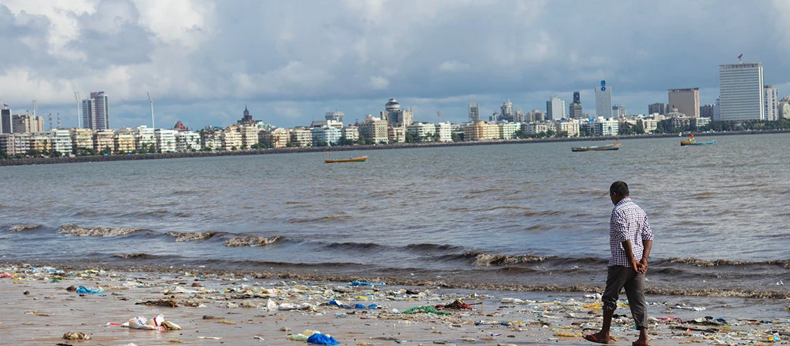 Man walking along the beach at Marine Drive in South Mumbai, India.