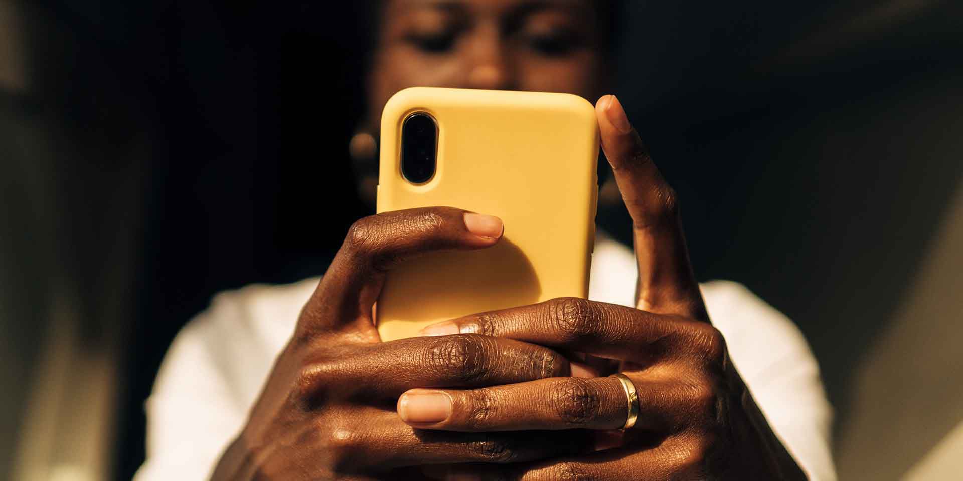 view from below of a black woman's hands with a mobile phone.