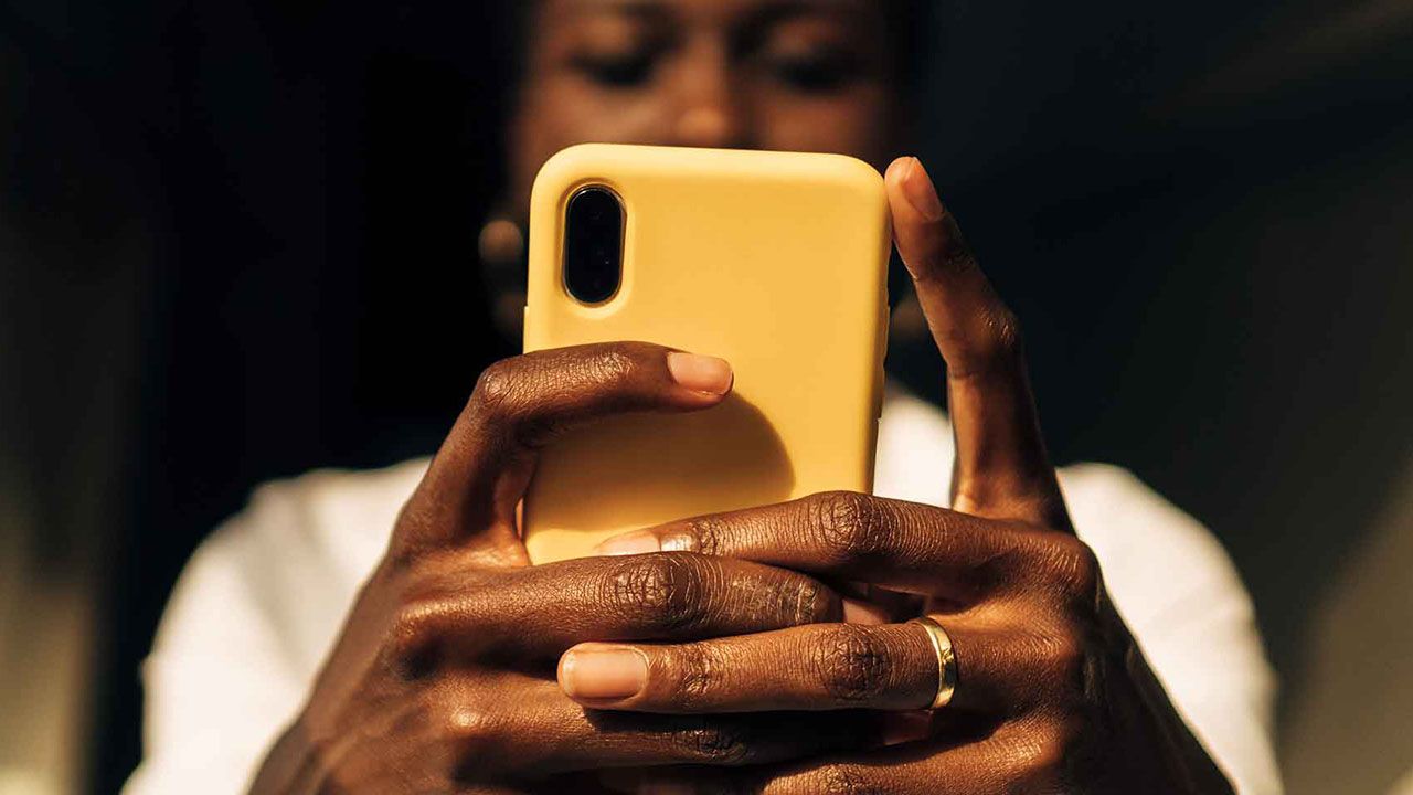 view from below of a black woman's hands with a mobile phone.