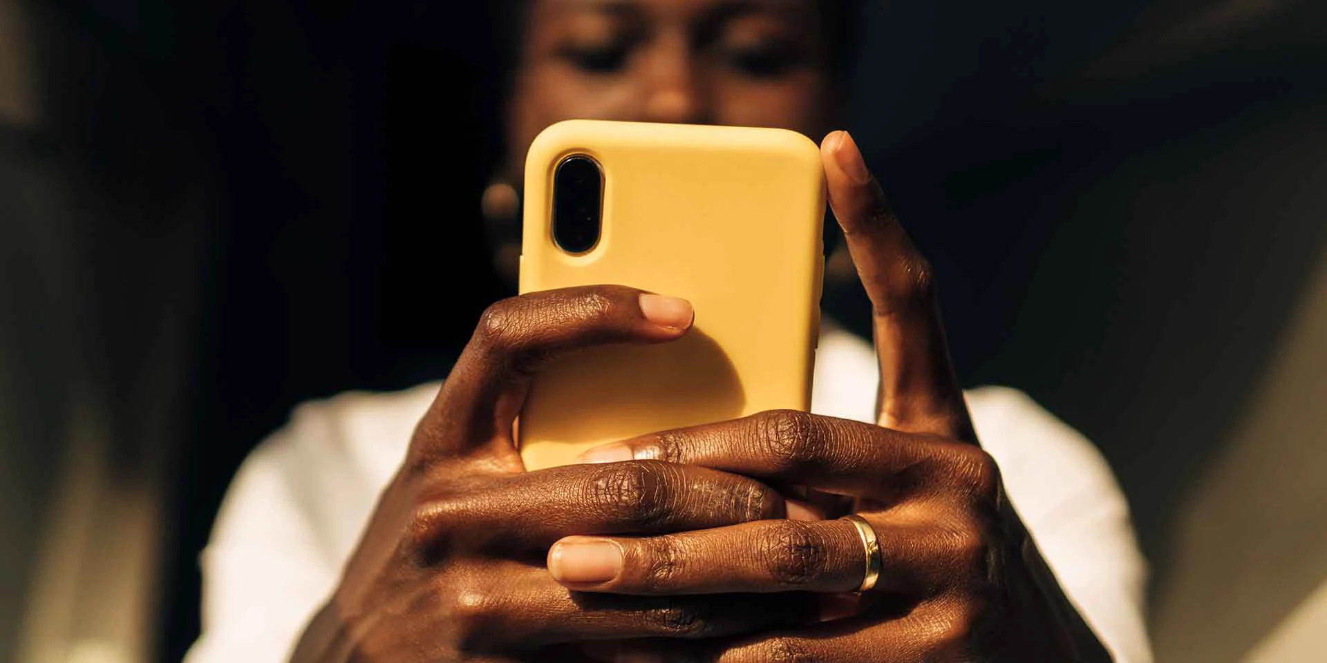 view from below of a black woman's hands with a mobile phone.