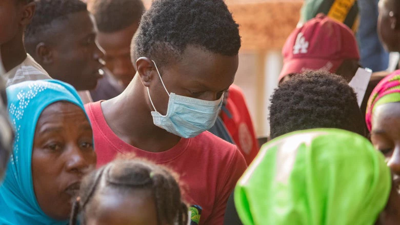 Un jeune homme porte un masque au milieu d'une foule au Mali. 