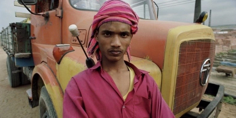 Portrait photo of young Bangladesh truck driver posing in front of his rig.