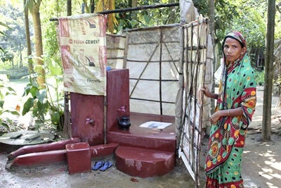 A happy customer shows off her new off-set pit latrine 