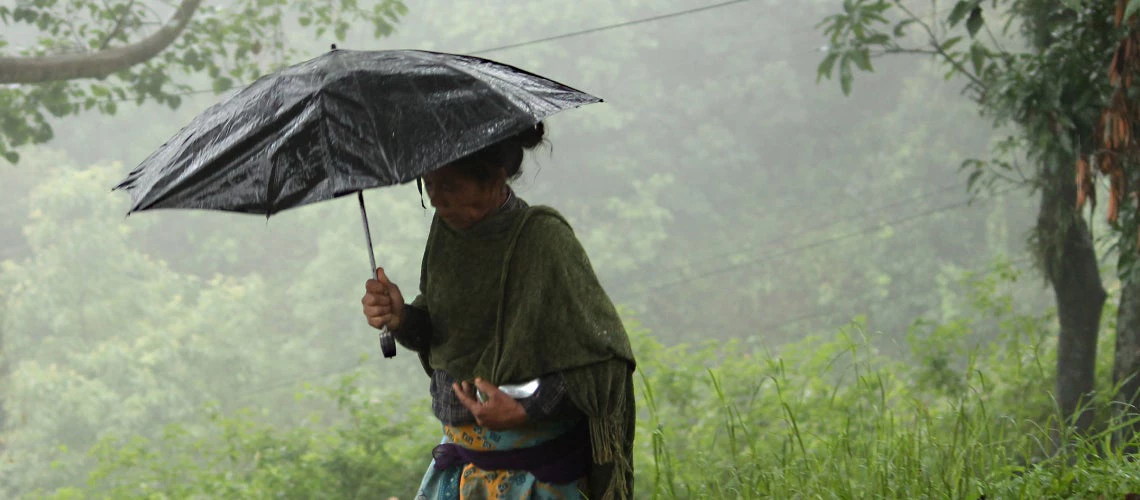 A woman walks under an umbrella in rural Nepal. Photo © Aisha Faquir/World Bank