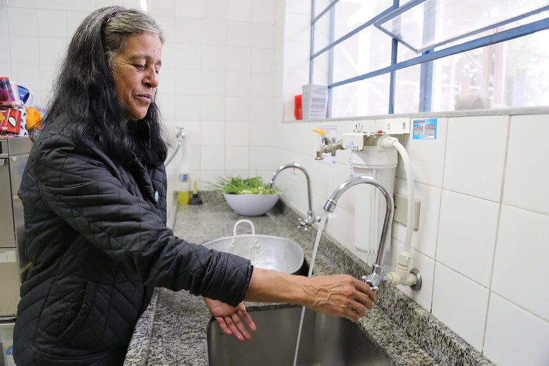 Mulher abre torneira, água sai