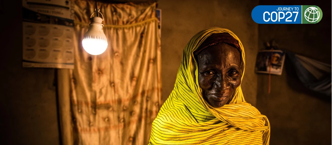 Portrait of 50-year old Aicha Diouf at her home in Senegal, standing near a ceiling light. Aicha got electricity at home recently. 