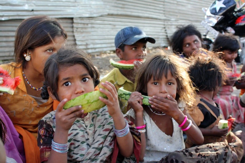 A girl in India eating watermelon along with her other family 