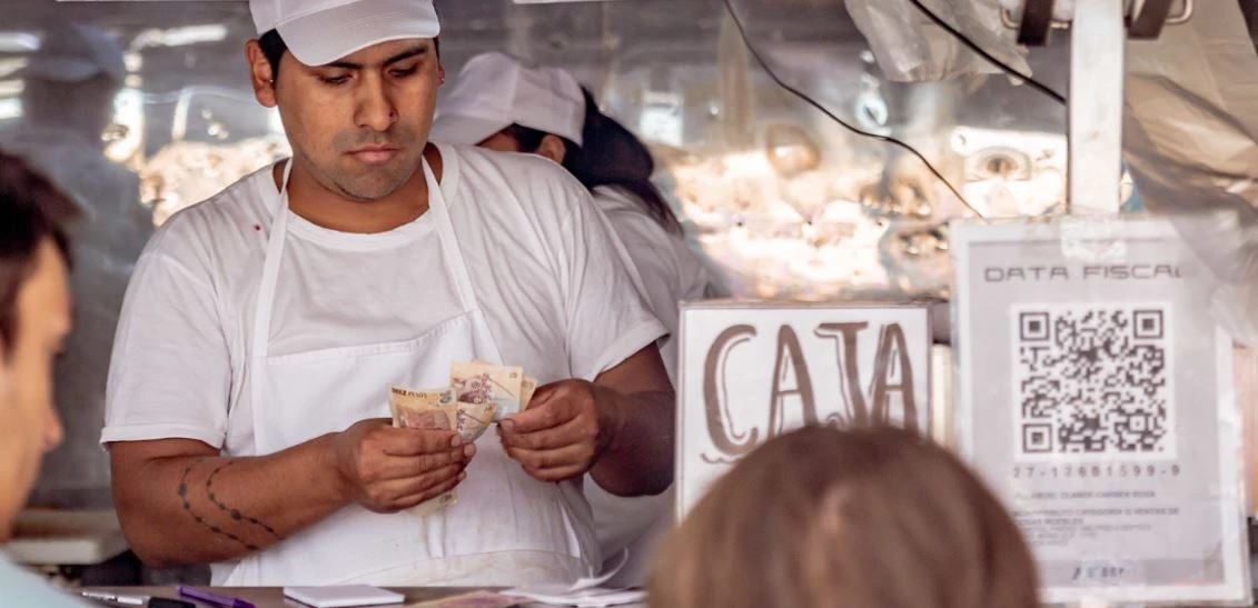 Vendedor cuenta dinero en un negocio pequeño en Buenos Aires 