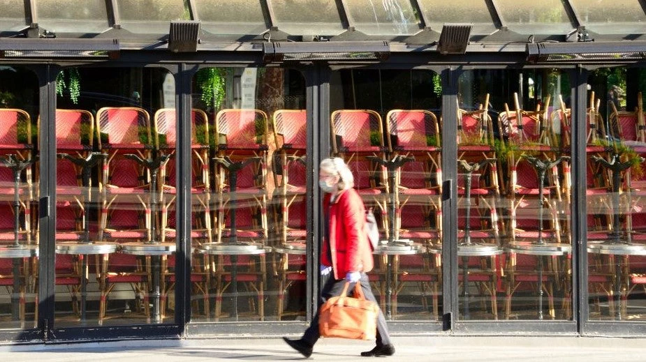 A woman wearing a mask walks in front of a restaurant that closed because of covid-19. The restaurant industry has suffered huge sales and job losses because of the covid-19 outbreak. (May 2020). Photo Credit: WorldPictures / Shutterstock.com