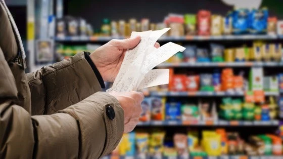 Minded man viewing receipts in supermarket and tracking prices