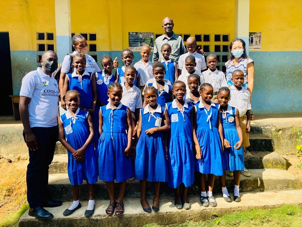 Students and their teacher in front of their school. 