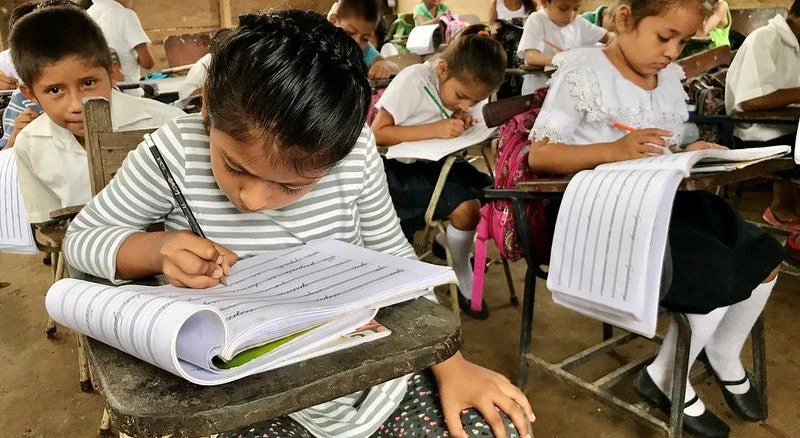 Niña escribiendo en una sala de clases con sus compañeros en la Comunidad Floripón, Siuna, Nicaragua.