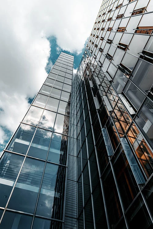 Glass building under cloudy sky. © Christian Wiediger on Unsplash