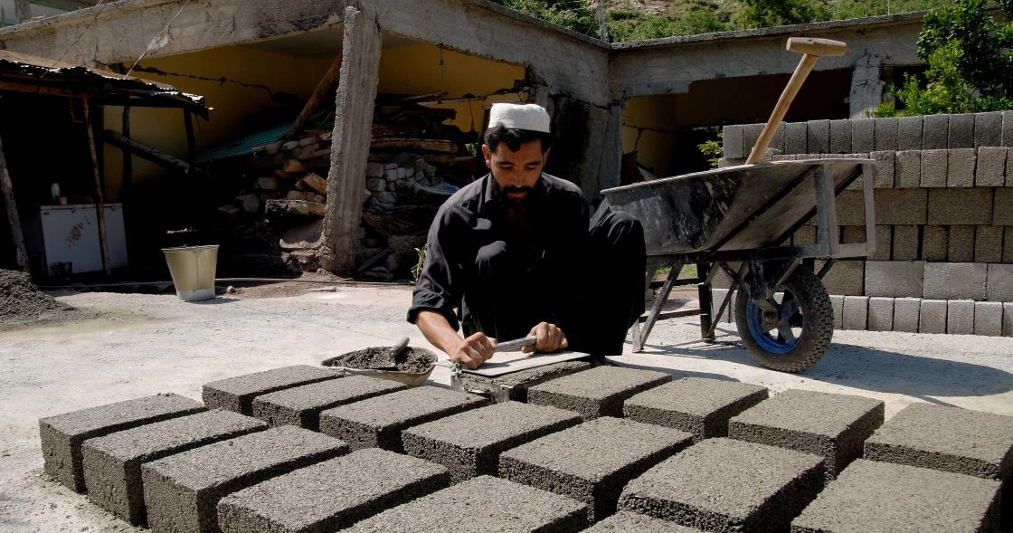 A person builds blocks near a reconstruction site in Pakistan. 