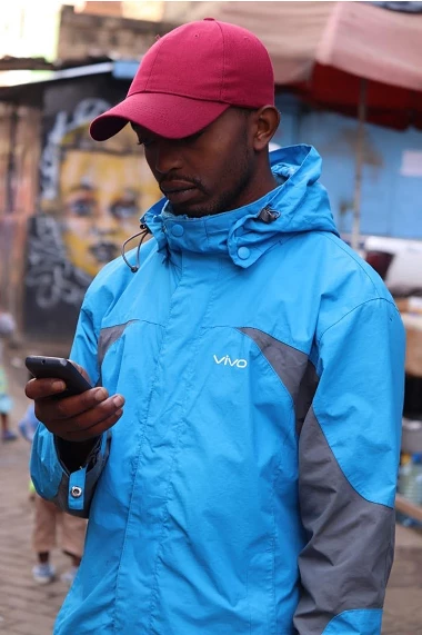 Young man in windbreaker, red cap, smart phone
