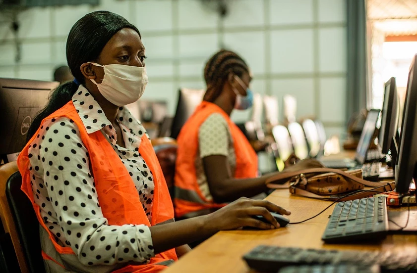 Women wearing masks, computers, training, orange vests, wooden table