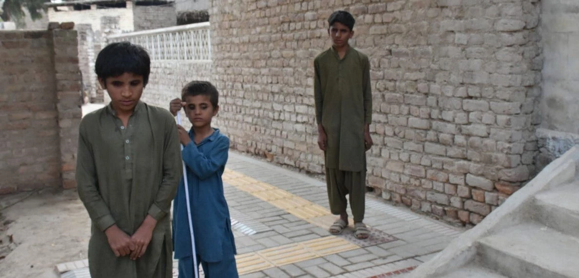 The three visually impaired boys are feeling tactile paving and practicing to use