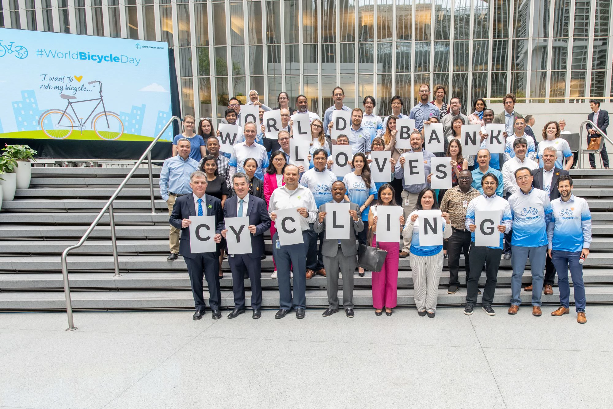 An photo of smiling World Bank staff holding a sign that says: World Bank Loves Cycling.